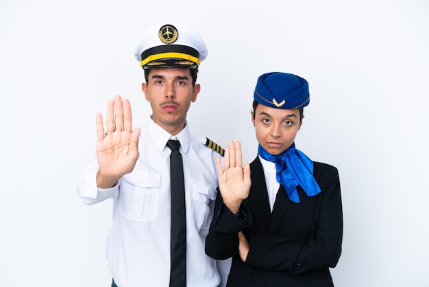 Piloto de avião e aeromoça de raça mista isolada em fundo branco fazendo gesto de parada negando uma situação que pensa errado