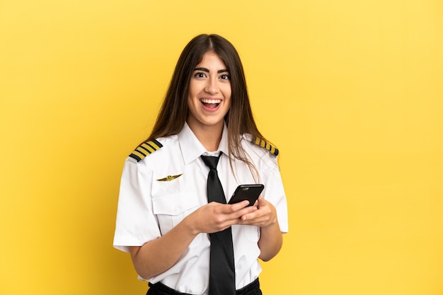 Piloto de avião isolado na parede amarela surpreso e mandando uma mensagem