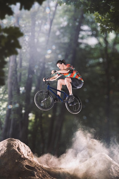 Piloto de bicicleta bmx brincando nas colinas da floresta