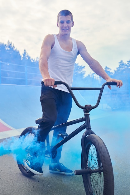 Piloto de bmx posando com fumaça azul