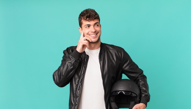 Piloto de moto sorrindo com uma expressão feliz e confiante com a mão no queixo, pensando e olhando para o lado