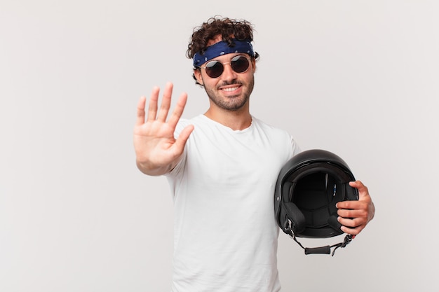 Piloto de motocicleta sorrindo feliz e alegre, acenando com a mão, dando as boas-vindas e cumprimentando você ou dizendo adeus