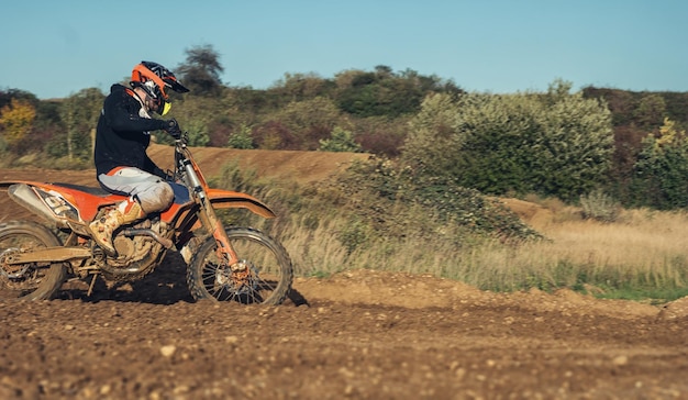 Foto piloto de motocross enduro acelerando em pista de terra