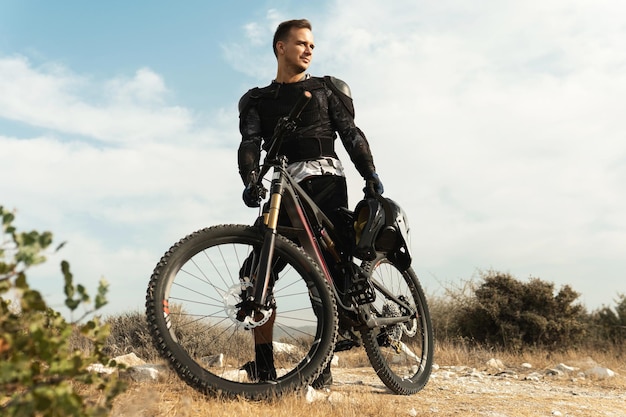 Piloto de descenso profesional totalmente equipado con equipo de protección y su bicicleta.