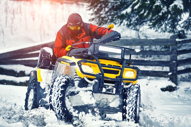 Piloto dirigindo na corrida de quadriciclo no inverno na floresta