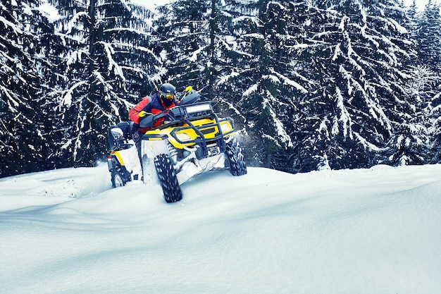 Piloto dirigindo na corrida de quadriciclo no inverno na floresta