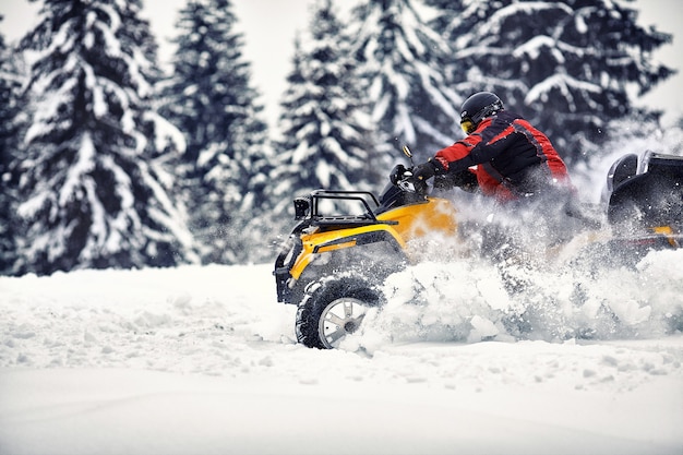 Piloto dirigindo na corrida de quadriciclo no inverno na floresta