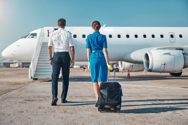 Piloto e aeromoça embarcando antes da viagem de trabalho