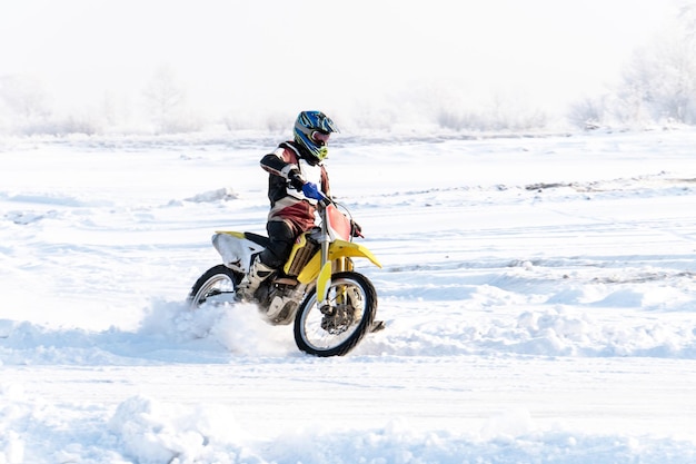 Piloto em uma motocicleta anda em volta das rodas um spray de neve e lama durante o motocross Cup Winter. Skid em uma estrada com neve. a neve sob as rodas de uma motocicleta Enduro.