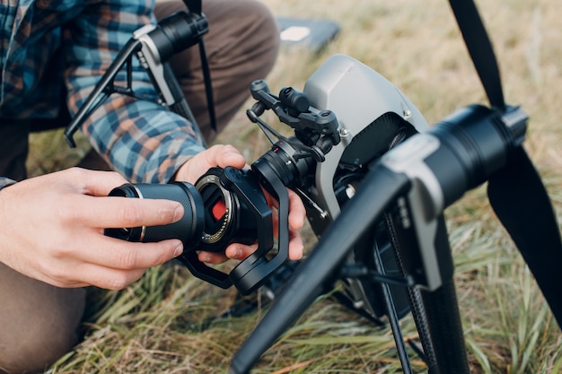 Piloto de hombre comprobando drone quadcopter y colocando la lente de la cámara antes del vuelo aéreo y la filmación