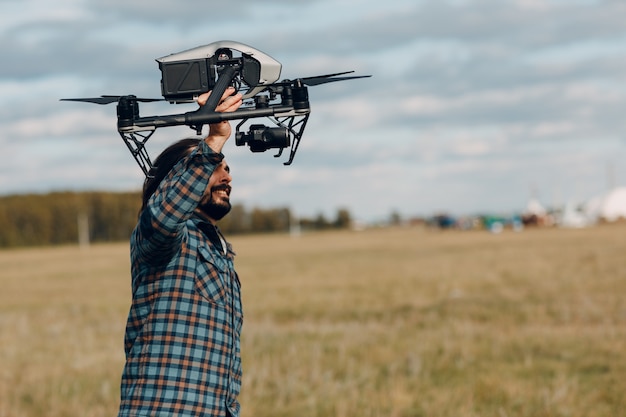 Piloto de hombre sosteniendo drone quadcopter DJI Inspire 2 en manos en el campo exterior.