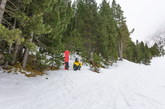Piloto livre com raquetes de neve e snowboard nas costas.