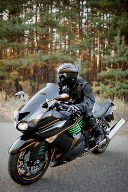 Piloto en una motocicleta conduciendo al atardecer: espacio para su texto, ciclista y motocicleta lista para montar