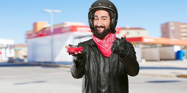 Piloto de motos sosteniendo un modelo de coche rojo.