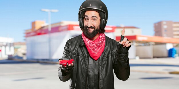 Piloto de motos sosteniendo un modelo de coche rojo.