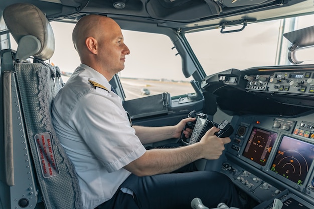 Foto piloto seguro sentado en la cabina y sosteniendo el volante