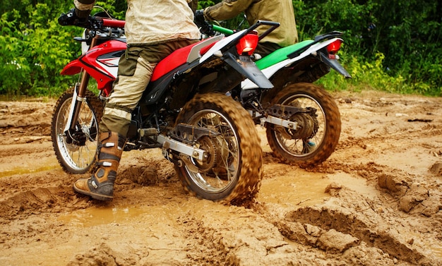 Foto pilotos de motocross correndo na lama do circuito offroad voando pelo ar passeios de moto pela lama com grande splashdriver espirrando lama em terreno molhado e lamacento piloto de motocross em um molhado e lamacento