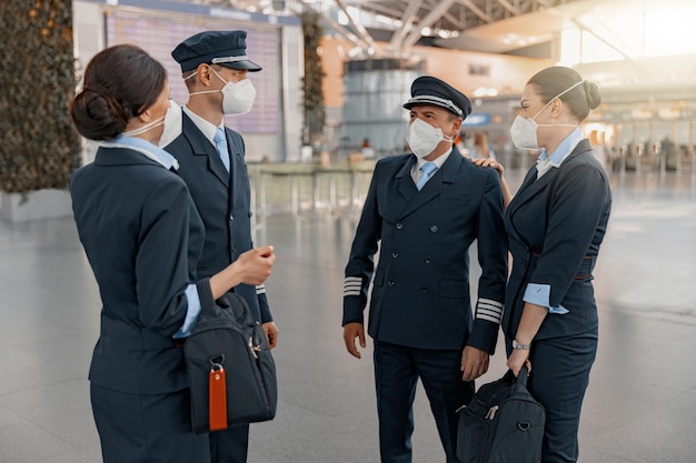 Pilotos masculinos e comissárias de bordo conversando no terminal do aeroporto