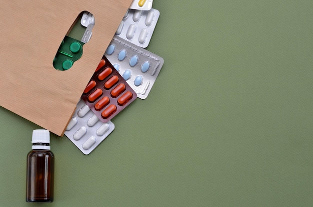 Pílulas de medicamentos diferentes em um saco de papel em um espaço de cópia de fundo verde