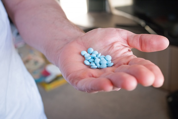 Pílulas na mão de um homem. overdosing na medicação. conceito de medicina e cuidados de saúde.