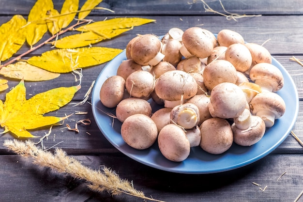 Pilzchampignons in einer Platte auf einem hölzernen Hintergrund.