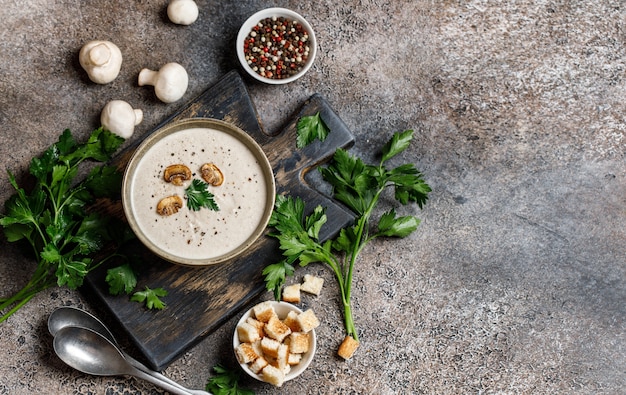 Pilzcremesuppe auf Schneidebrett mit Zutaten