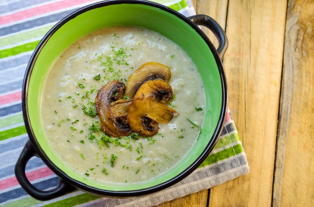 Pilzcremesuppe in einer Terrine auf einem Holztisch