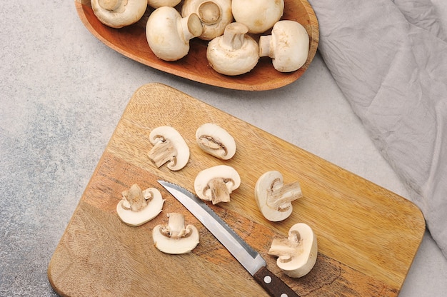 Pilze in einem Holzteller auf einem Grau mit einem Messer