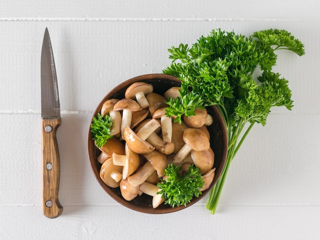 Pilze Steinpilz, Petersilie und ein Messer auf dem weißen Tisch des Dorfes