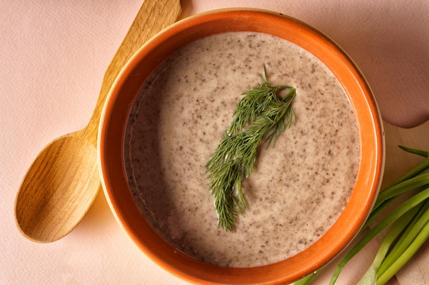 Pilzkremsuppe in einem Plattenbrot-Löffel über rosa Hintergrund