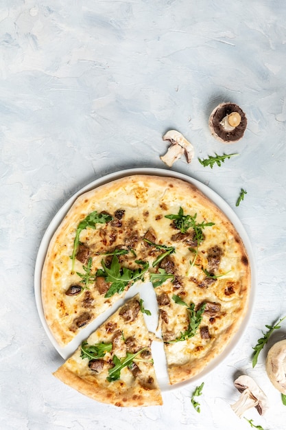 Pilzpizza, Mozzarella, Champignons und Rucola. vertikales Bild. Ansicht von oben. Platz für Text