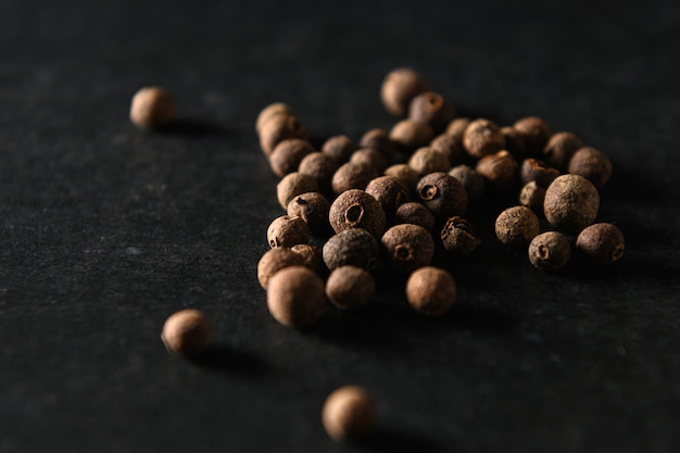 Foto piment schwarze pfefferkörner, gewürz für lebensmittel, auf grauem hintergrund gestreut