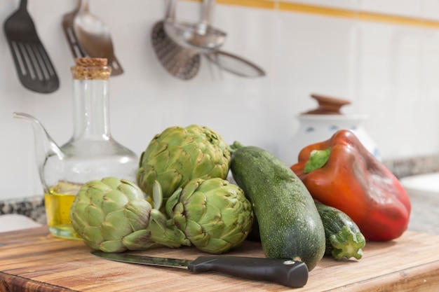 Pimenta de abobrinha alcachofra e óleo na mesa de cozinha alimentos frescos