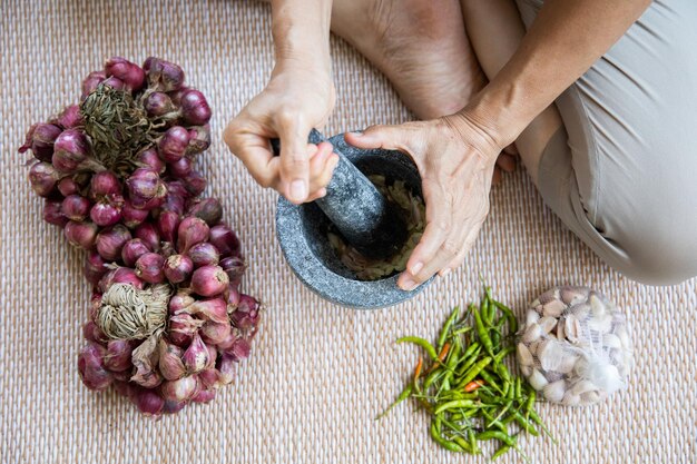 Pimenta picada à mão com alho-pimenta vermelha por argamassa de pedra em tapete