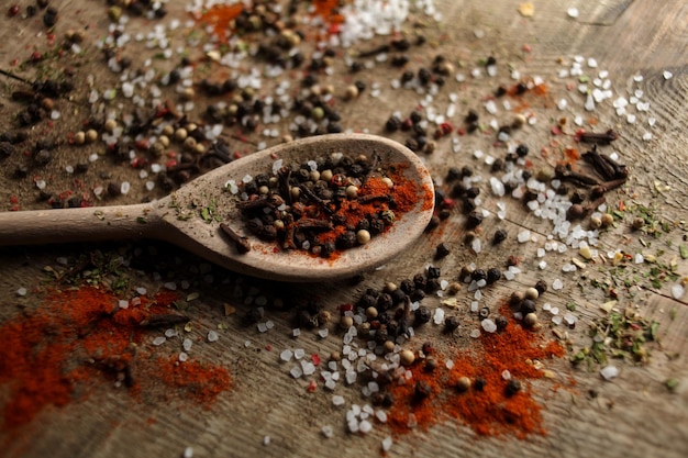 Pimenta preta ervilhas sal marinho pimenta em pó especiarias em uma colher em um fundo de madeira