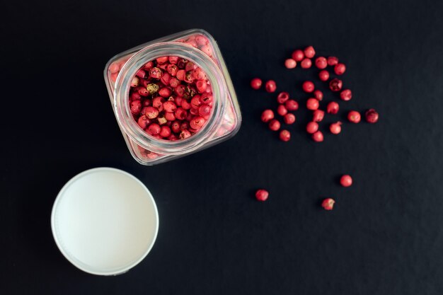 Pimenta rosa em uma jarra de vidro em um fundo escuro, profundidade de nitidez rasa, vista acima