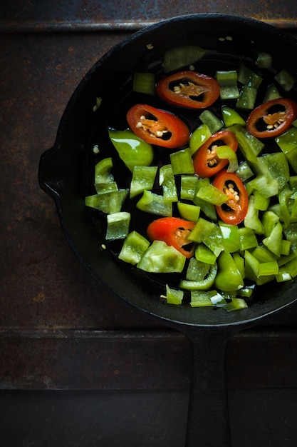 Pimenta verde e pimentão em uma frigideira de ferro fundido