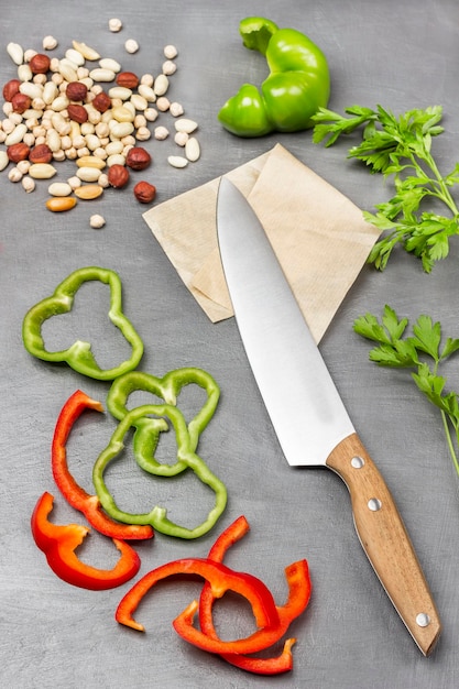 Pimenta verde e vermelha picada Faca de cozinha em nozes de papel e raminhos de salsa de grão de bico na mesa