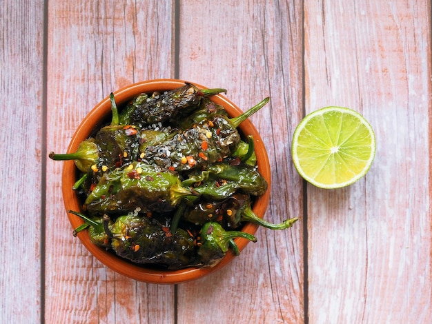 Pimenta verde Padron assada ou frita à espanhola em tigela de cerâmica e limão