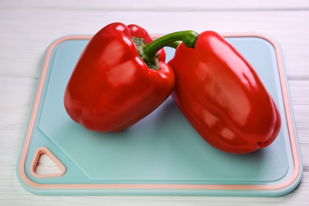 Pimenta vermelha doce e uma faca em uma tábua, em uma superfície de madeira branca