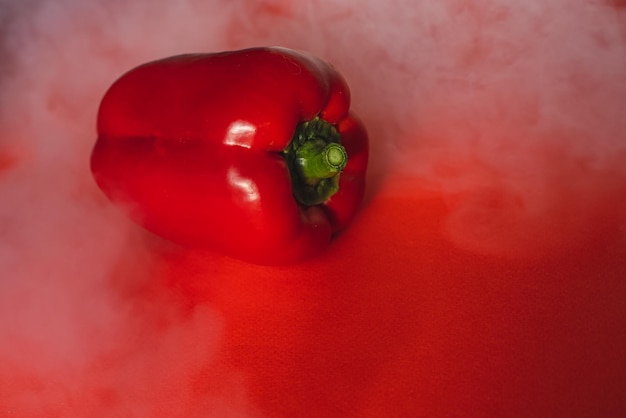 PIMENTA VERMELHA DOCE fresca NO FUNDO VERMELHO Com fumaça ao redor da foto da pimenta para o menu nutrição adequada legumes frescos