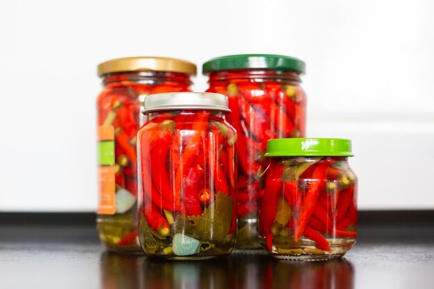 Foto pimenta vermelha picada em frascos em uma mesa preta de conservas de legumes