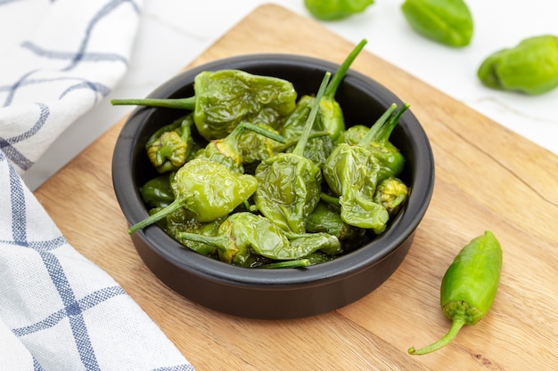 Pimentas de Padron cozidas em uma tigela na mesa de madeira. Aperitivo tradicional espanhol