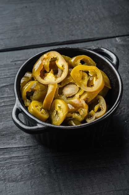 Pimentas Jalapeño fatiadas em potes, na mesa de madeira preta