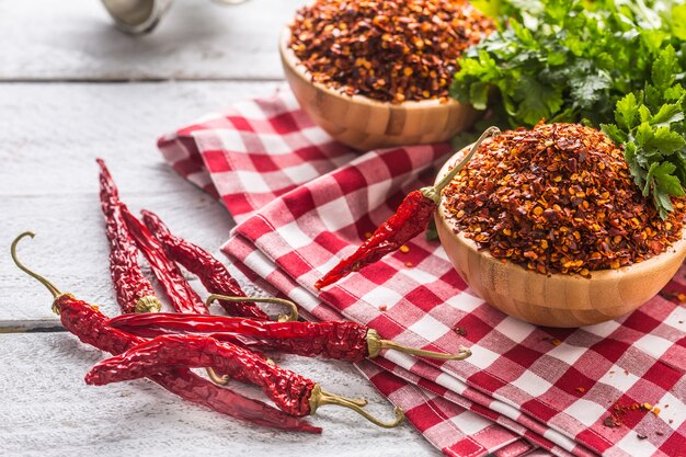 Pimentas secas e trituradas em tigelas de madeira com ervas de salsa.