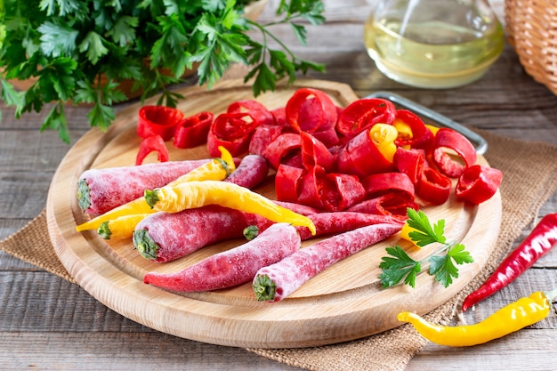 Pimentas vermelhas congeladas. pimenta congelada em uma placa de madeira em cima da mesa. alimentos congelados. vegetais congelados.