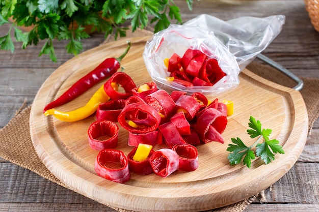 Pimentas vermelhas congeladas. Pimenta congelada em uma placa de madeira em cima da mesa. Alimentos congelados. Vegetais congelados.