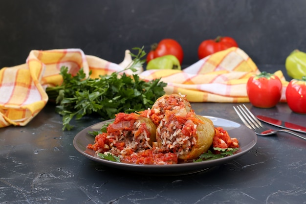 Pimentões recheados com carne, arroz e molho de tomate localizados em um prato no escuro