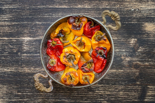 Pimentões vermelhos e amarelos assados Pimentas em uma assadeira em uma mesa de madeira Um prato vegetariano saudável e delicioso Closeup vista superior