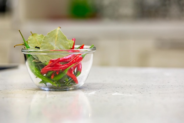Pimentões vermelhos e verdes quentes com especiarias em uma tigela para molho de pimenta saboroso em tigela no fundo da cozinha